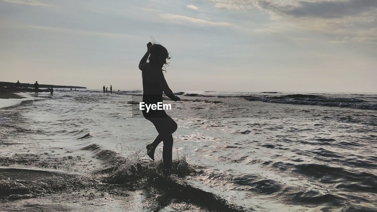 Full length of girl standing on beach against sky