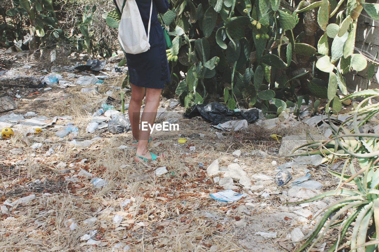 Low section of woman walking on field against trees