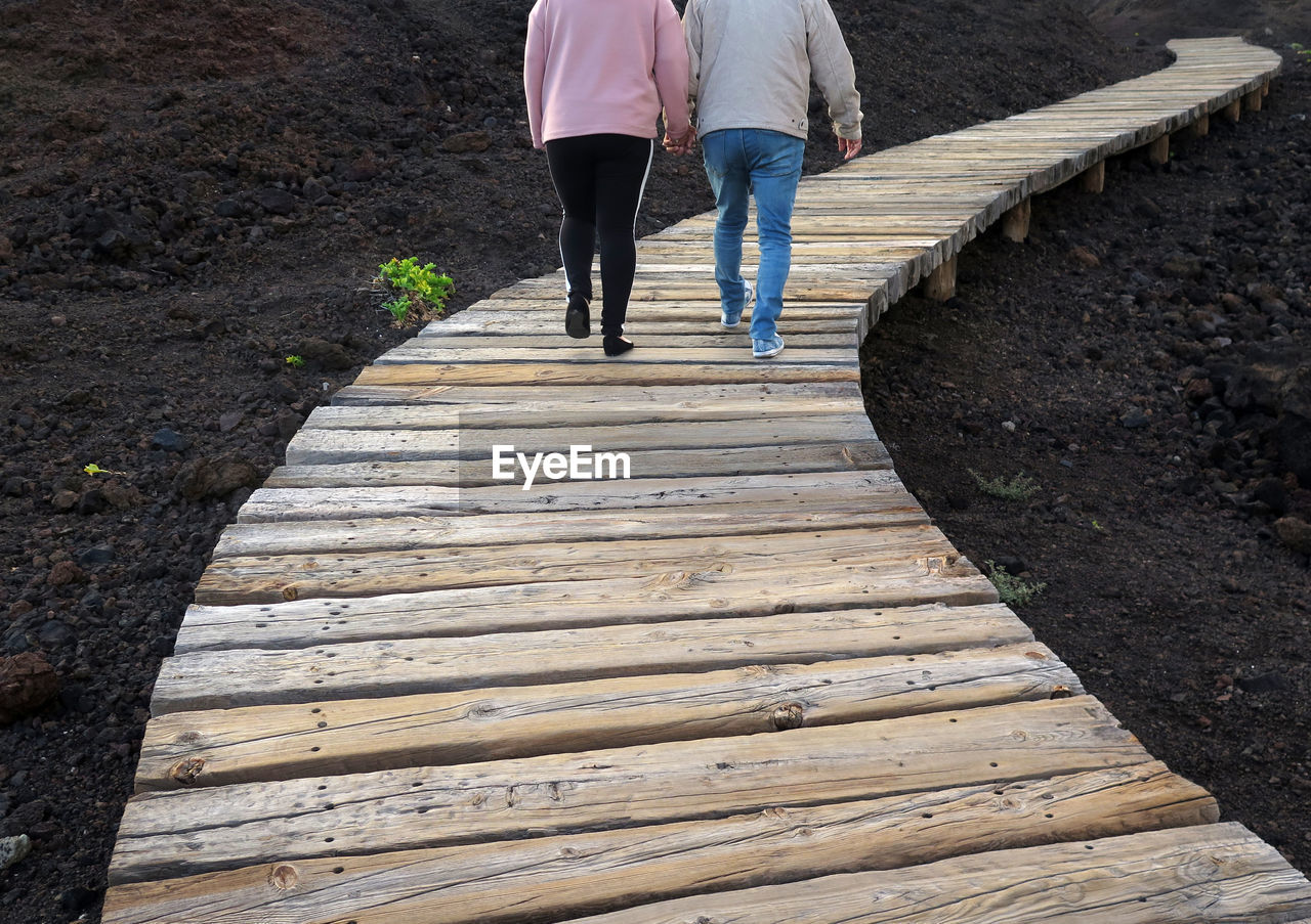 Low section of couple walking on footpath