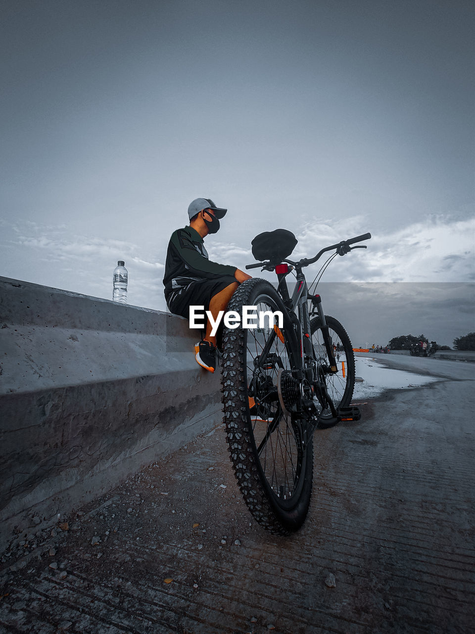 Man riding bicycle on road against sky