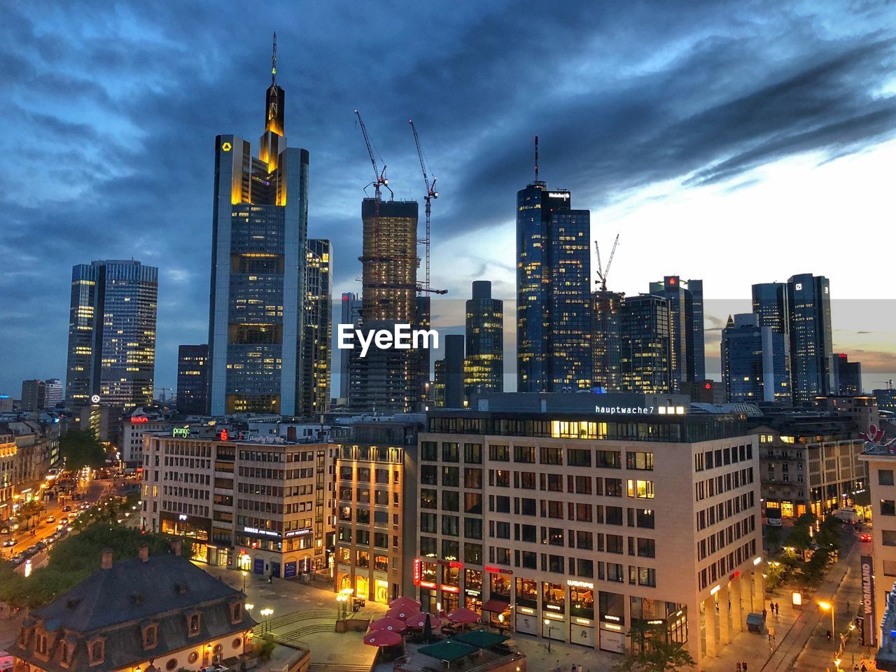 Illuminated buildings in city against sky at dusk.  frankfurt, germany