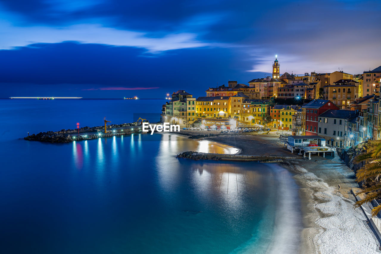 buildings by sea against sky at sunset