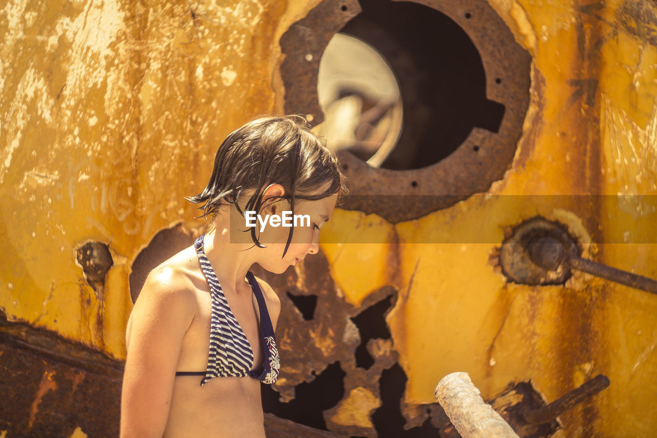 Close-up of girl standing against rusty metal