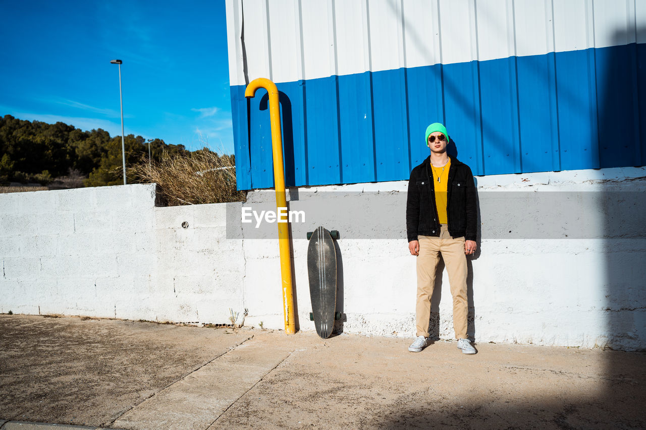 YOUNG MAN STANDING AGAINST WALL