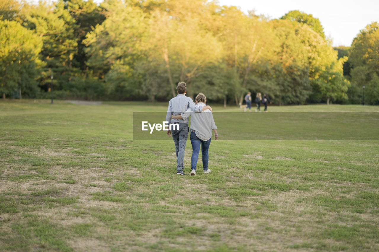 REAR VIEW OF CHILDREN ON GRASSY LANDSCAPE