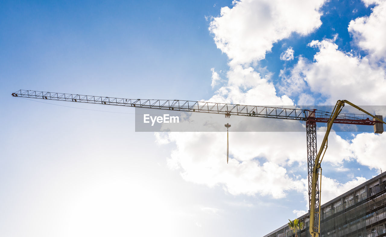 LOW ANGLE VIEW OF CRANES AGAINST SKY