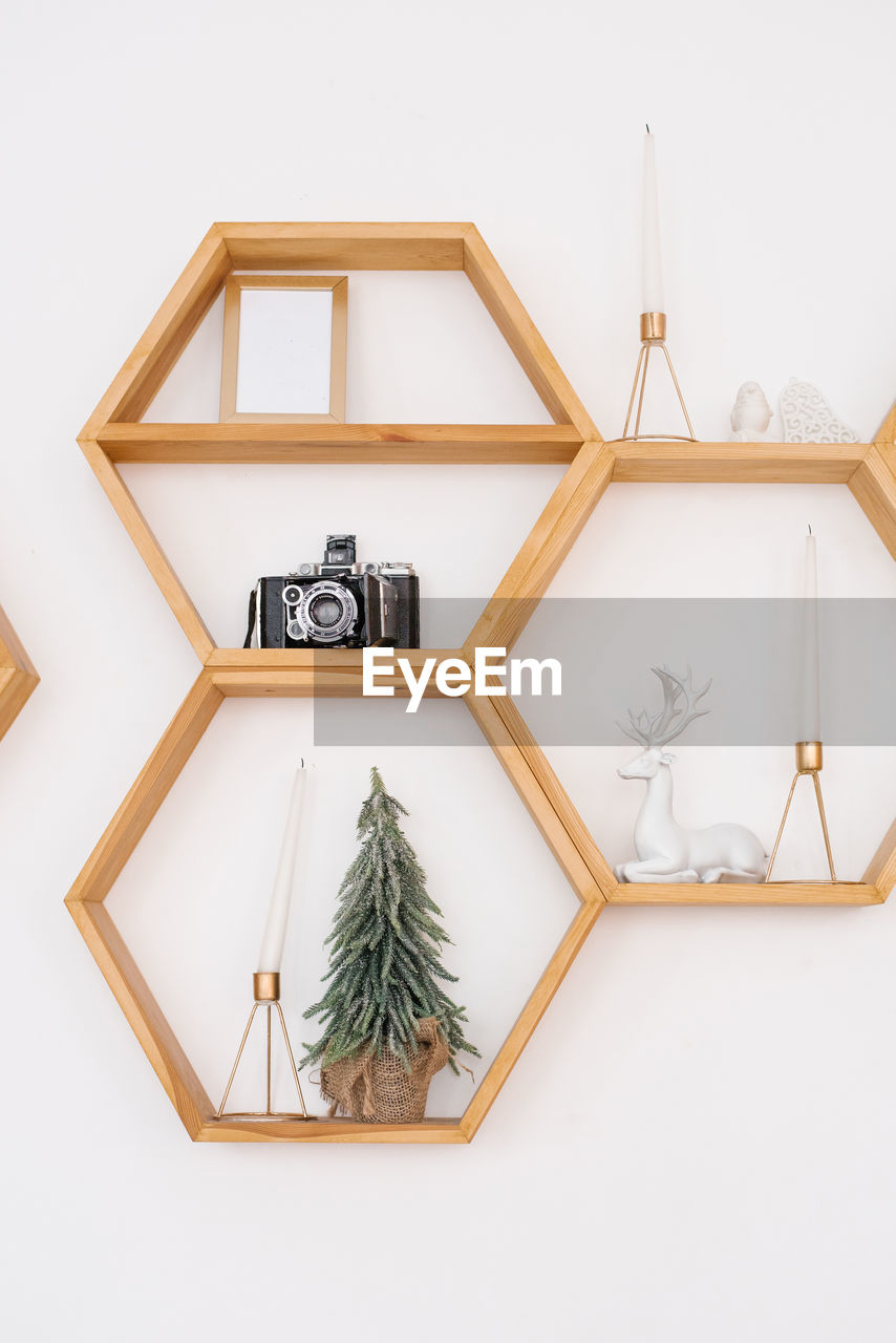 Pine wood hexagonal shelves on the wall with a variety of decor. christmas tree, retro camera