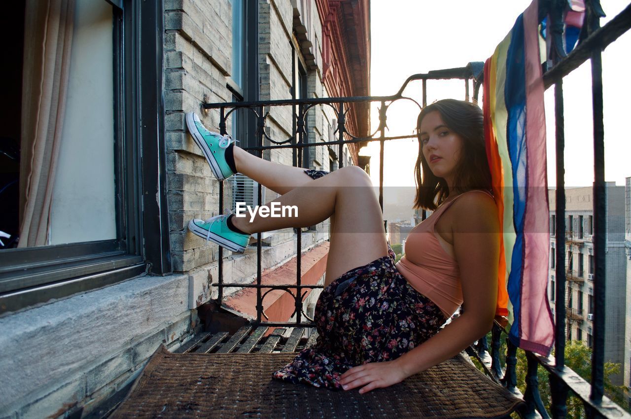 YOUNG WOMAN SITTING ON WINDOW