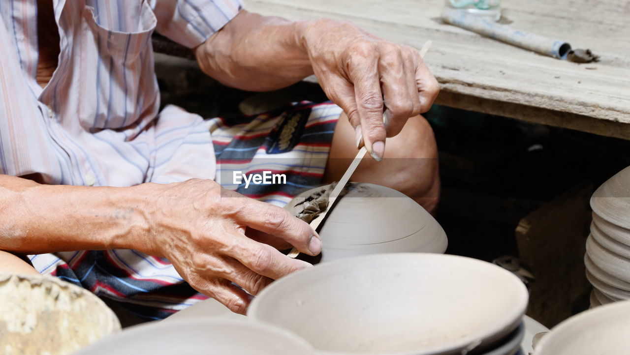 Midsection of man working on pottery wheel at workshop