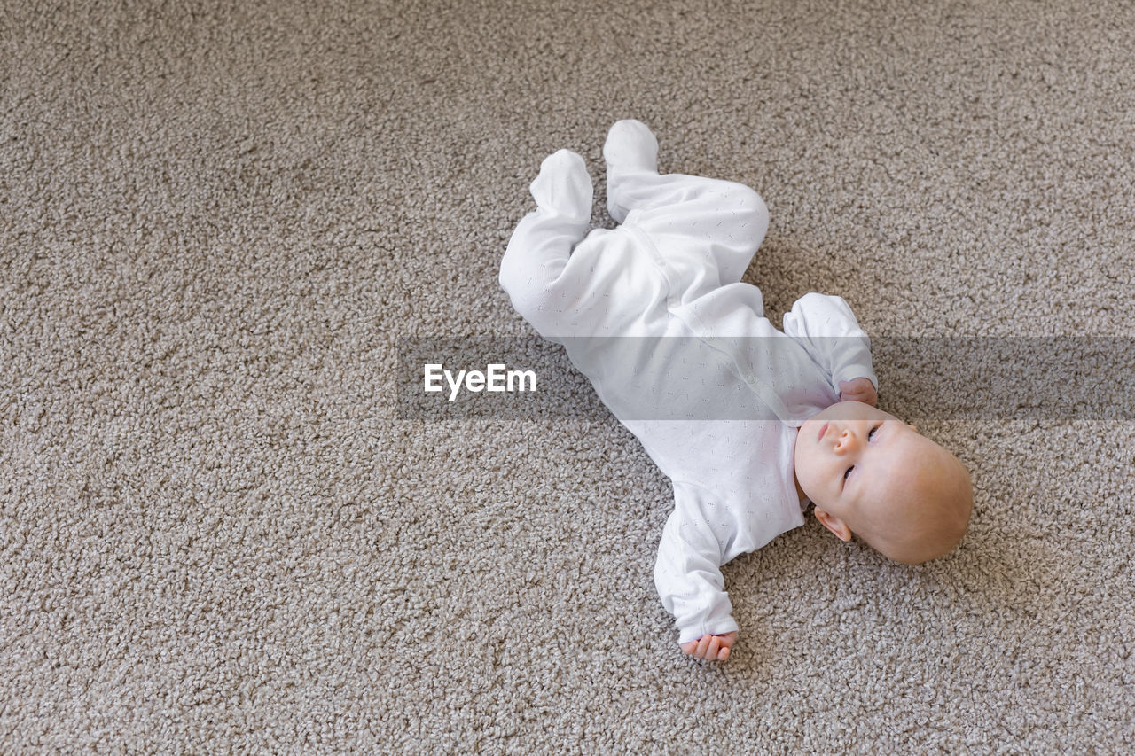 HIGH ANGLE VIEW OF BABY LYING ON BED