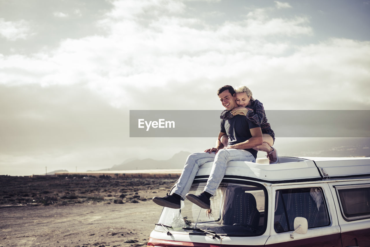 Young couple relaxing on van at beach
