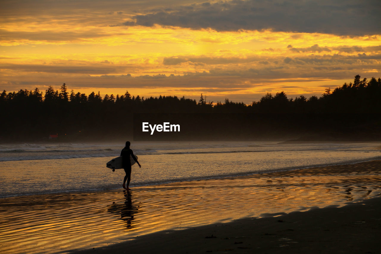 Silhouette of a surfer on beach at sunset