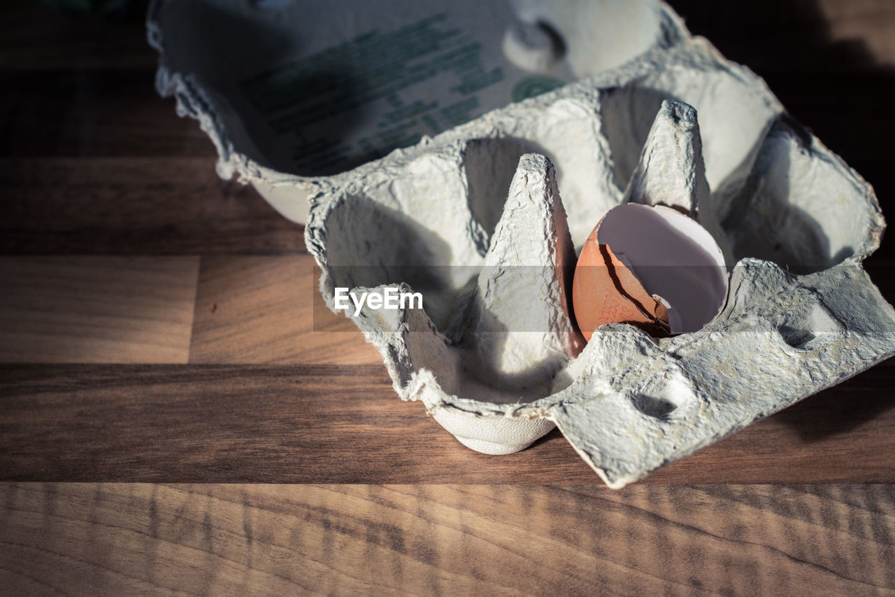 Eggshell in carton on wooden table