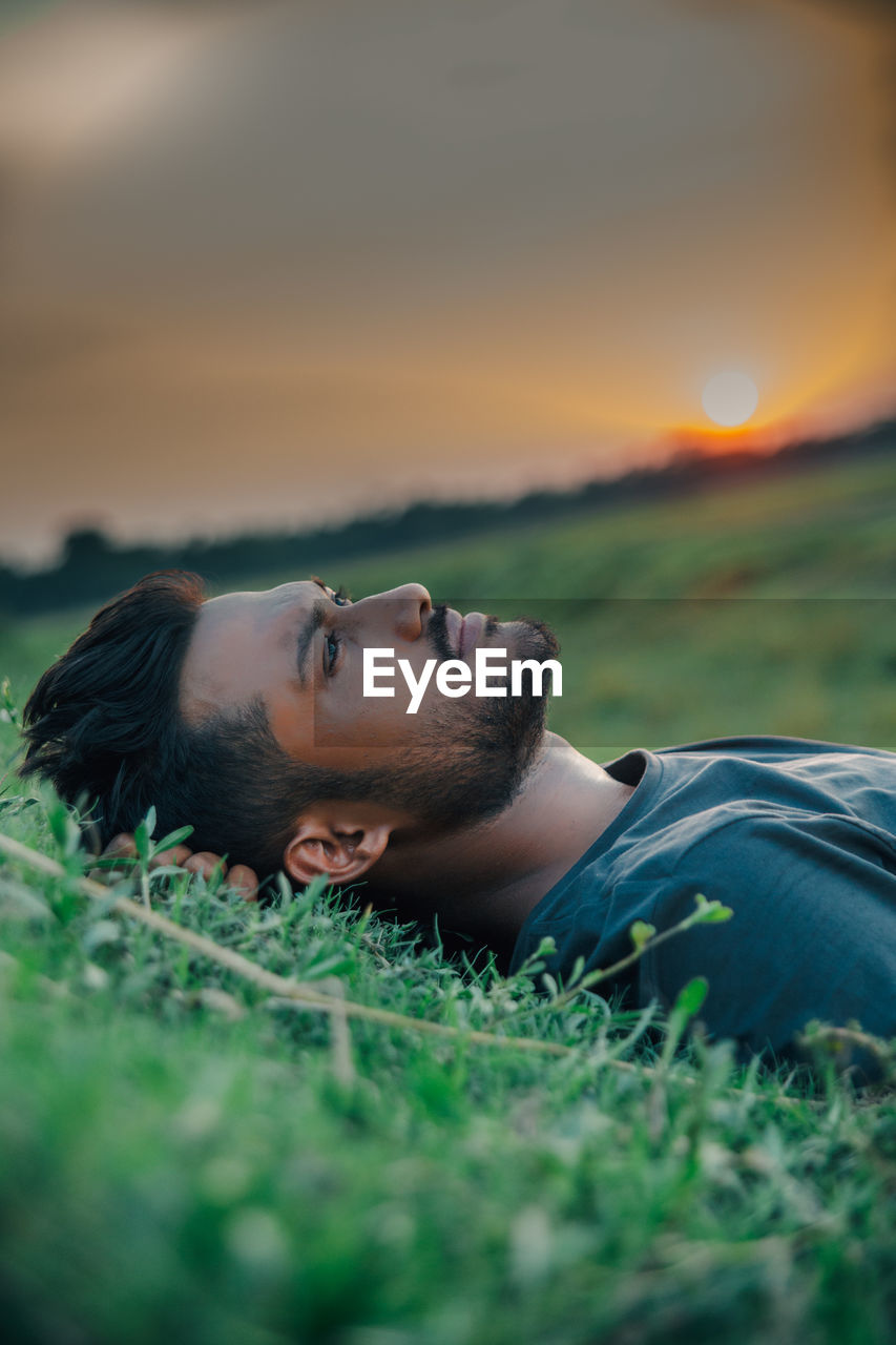 Laying on ground of grasses and the sun sets