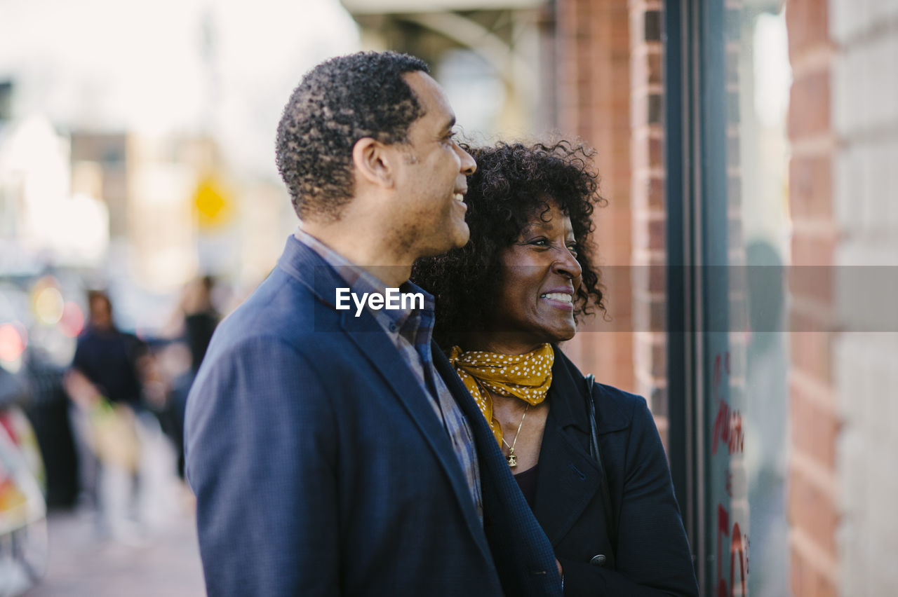 Smiling couple doing window shopping in city