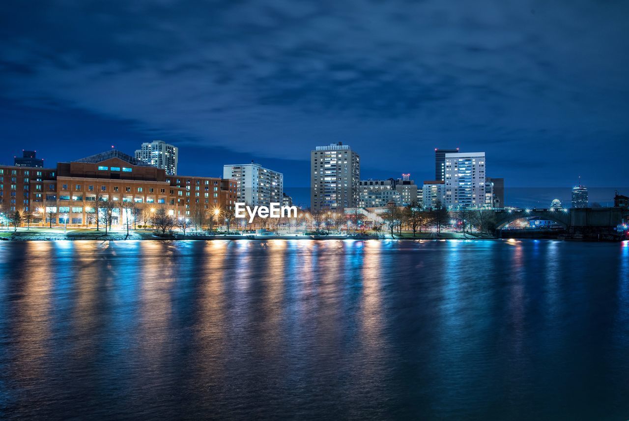 Lake and illuminated buildings against sky in city at night