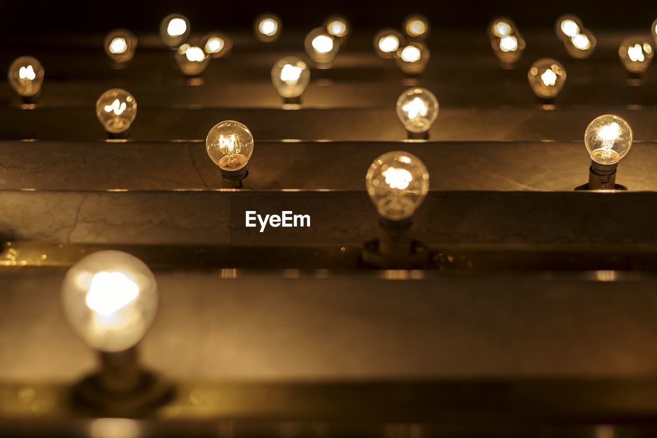 Low angle view of illuminated light bulbs hanging at night