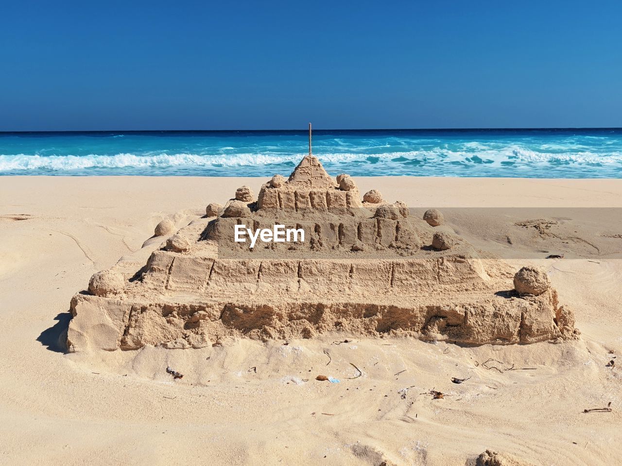 Sand castle at the beach against blue sky