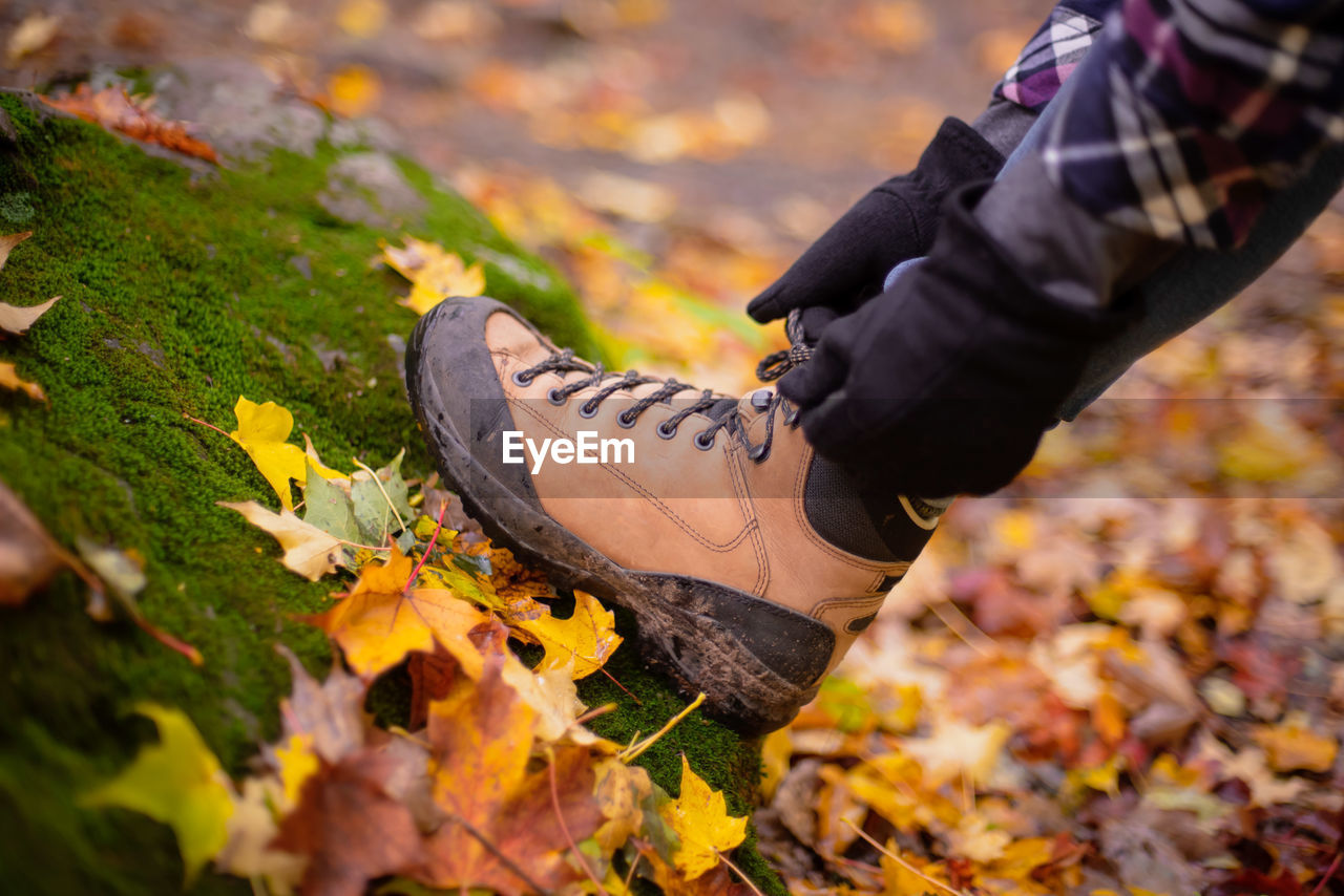 Low section of man tying shoelace on field during autumn