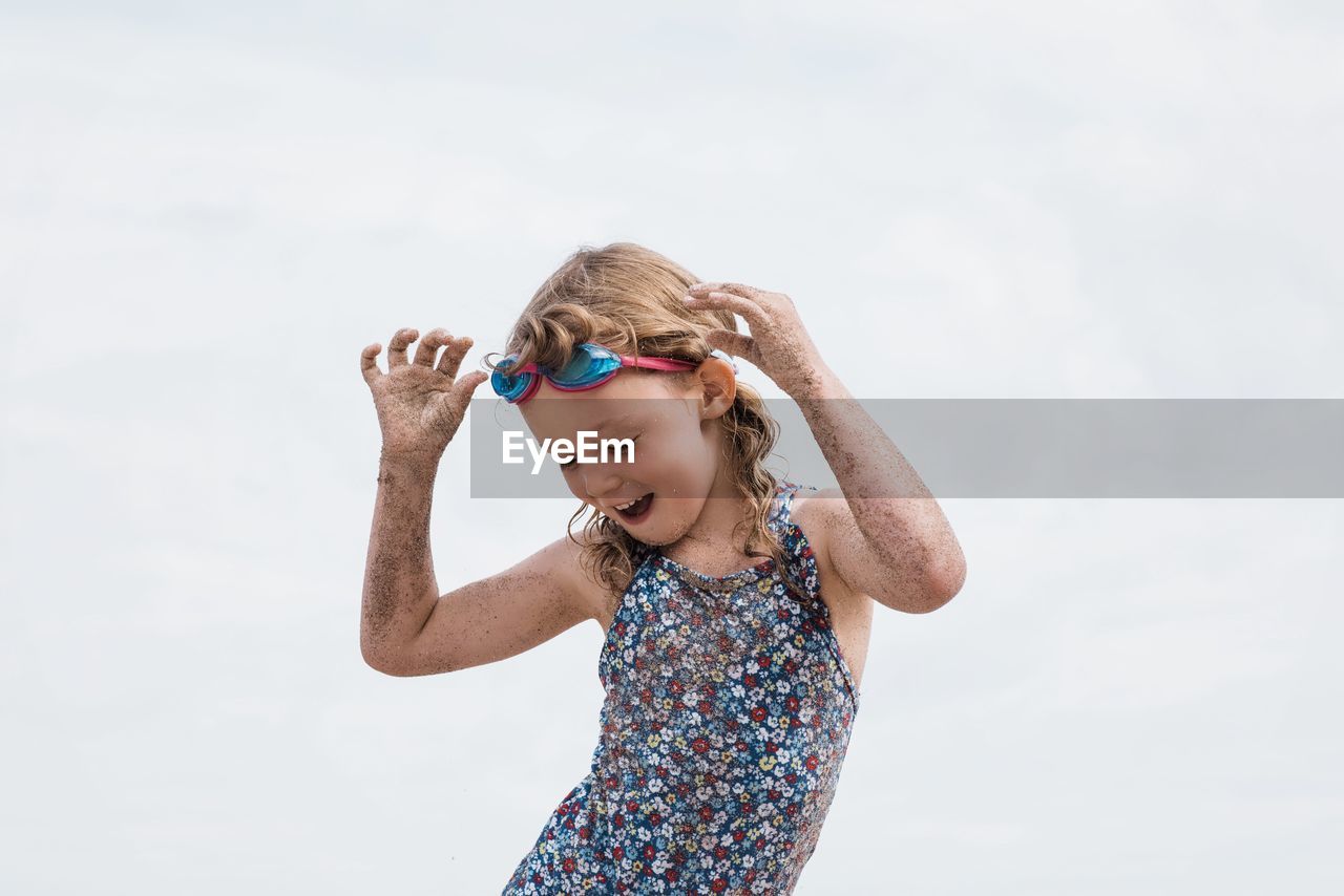 Girl with goggles on dancing having fun at the beach in summer