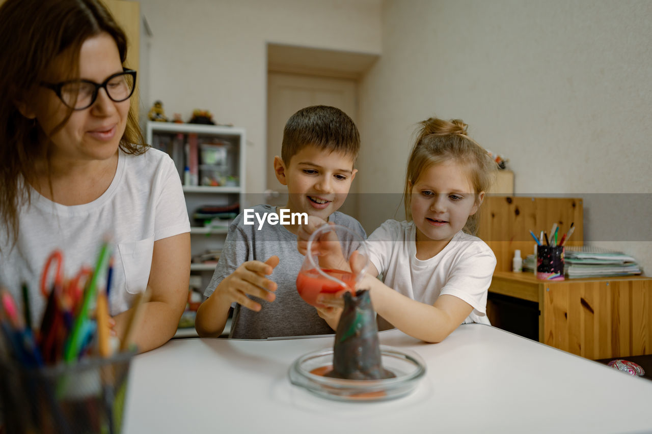 Mom and children at home are conducting an experiment with a volcanic eruption.