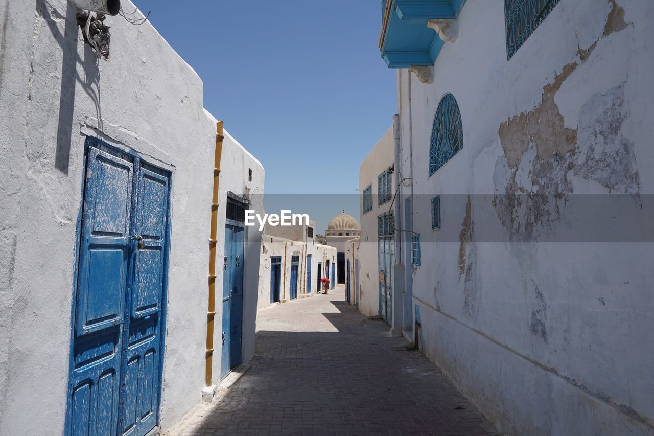 Narrow alley amidst buildings in city against sky