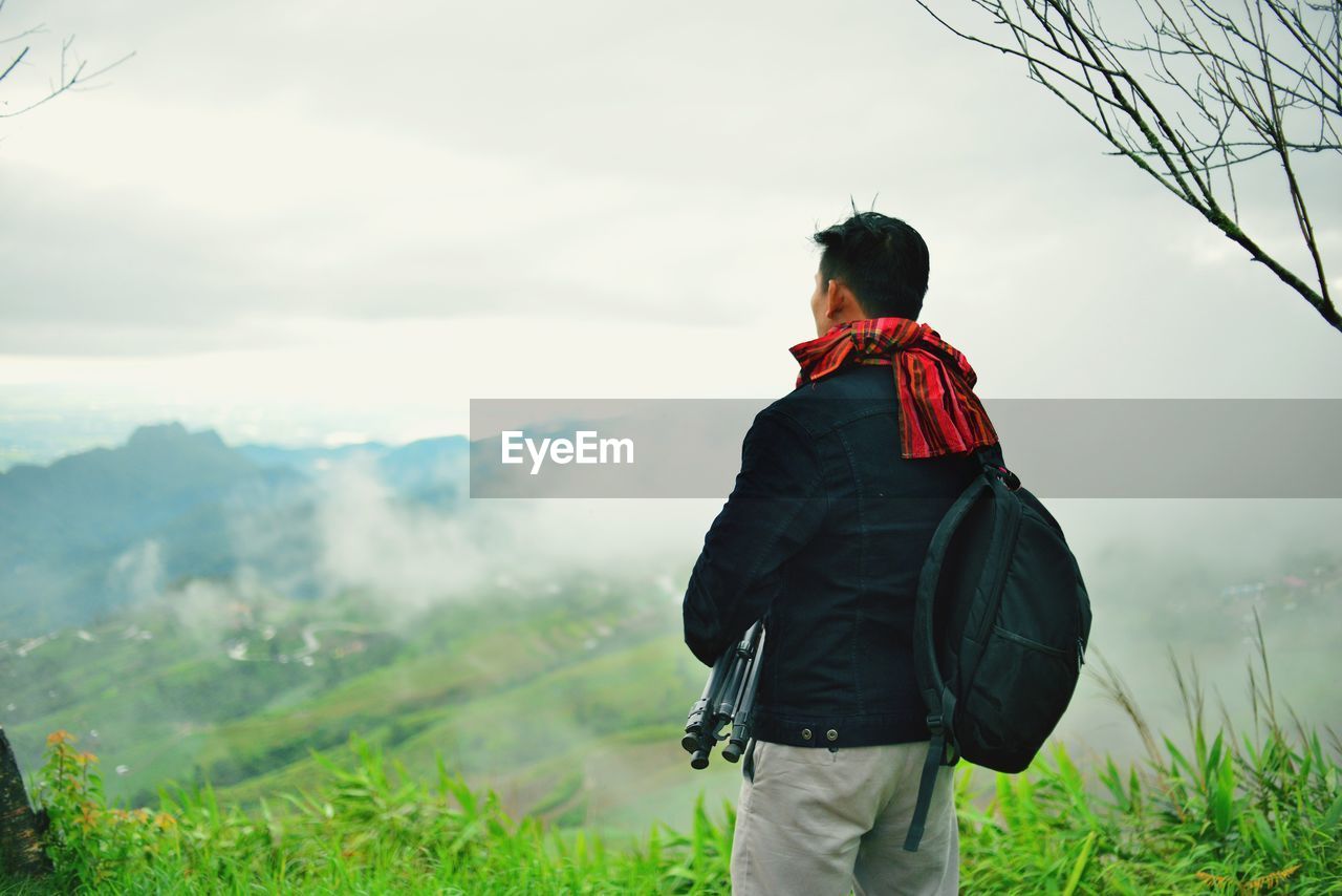 Rear view of man standing on mountain against sky