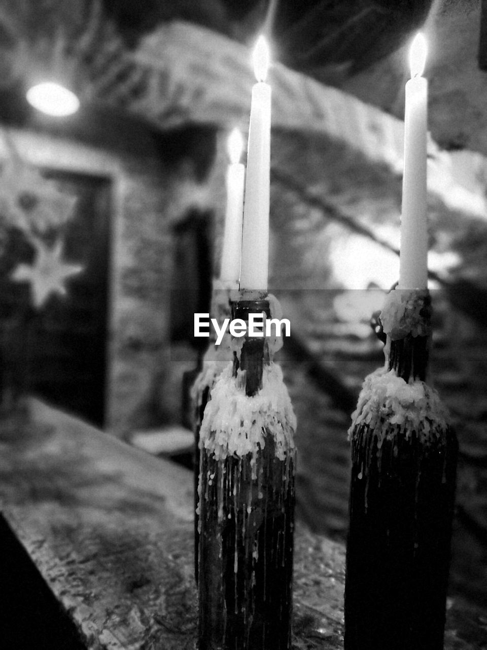 Close-up of lit candles on bottles at railing