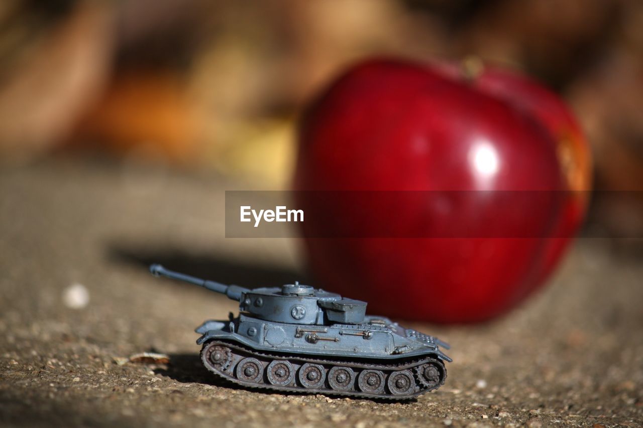 Close-up of armored tank against apple on footpath