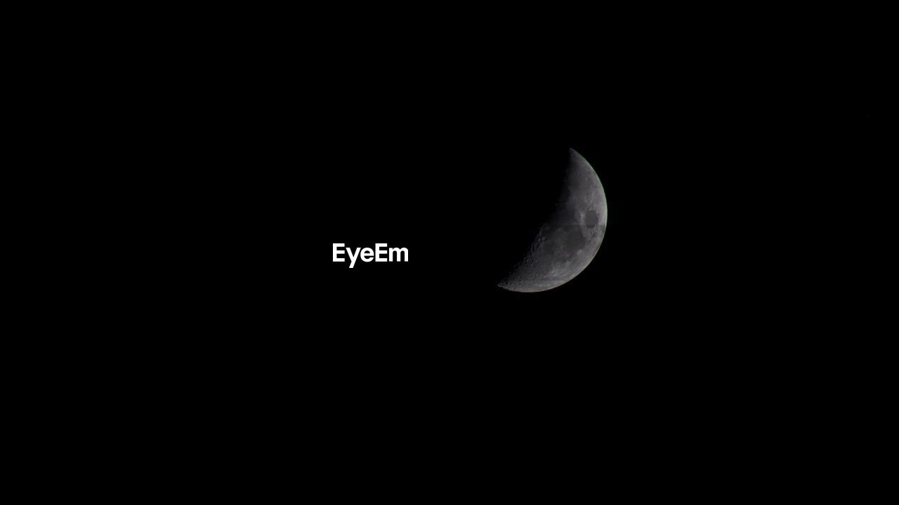 LOW ANGLE VIEW OF HALF MOON AGAINST CLEAR SKY AT NIGHT