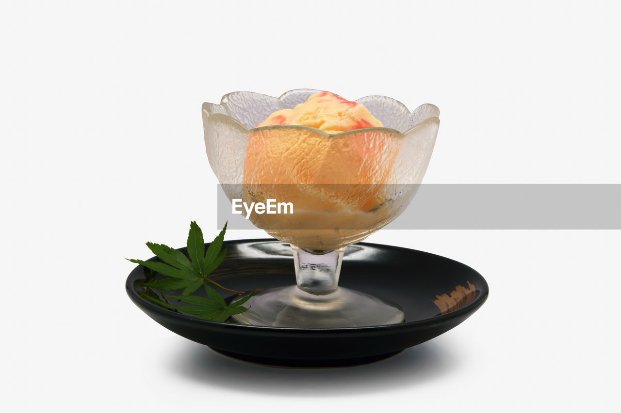 CLOSE-UP OF ORANGE SLICE IN GLASS AGAINST WHITE BACKGROUND