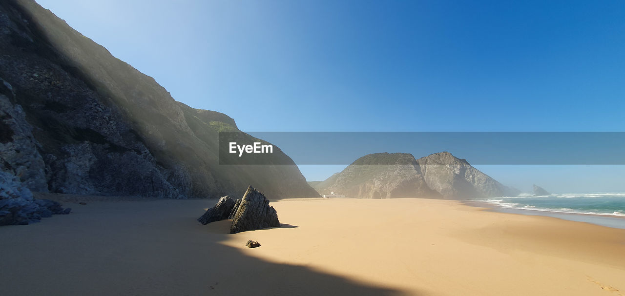 Scenic view of beach against clear blue sky