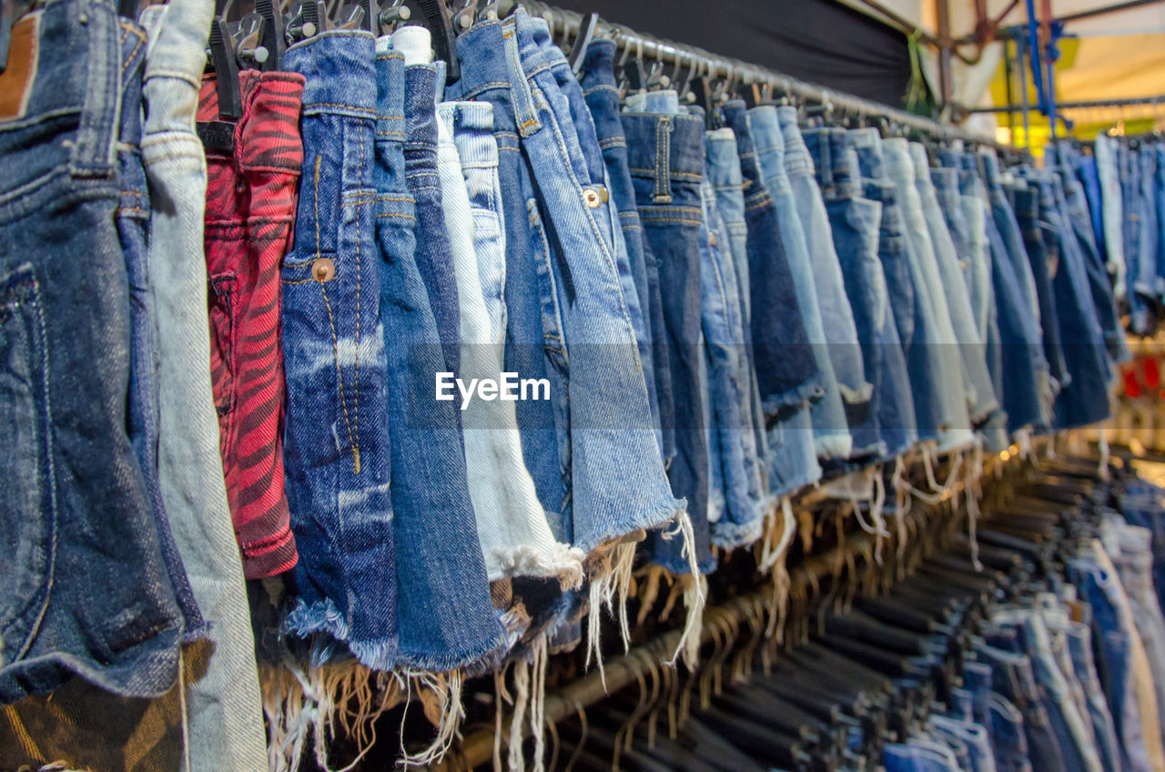 Close-up of denims hanging for sale at clothing store