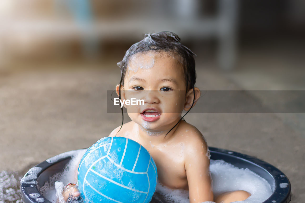 Portrait of cute baby girl sitting in tub