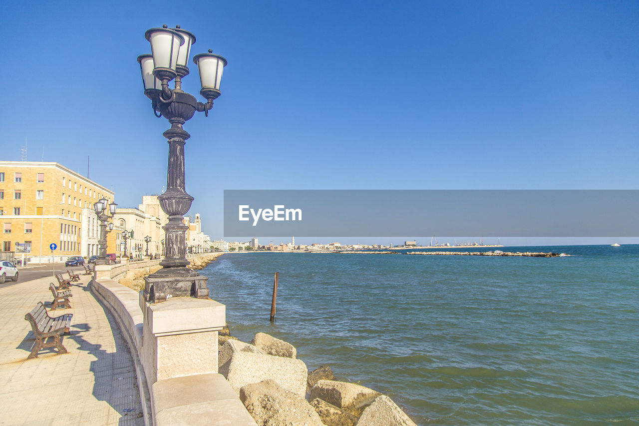 Street light by sea against clear sky