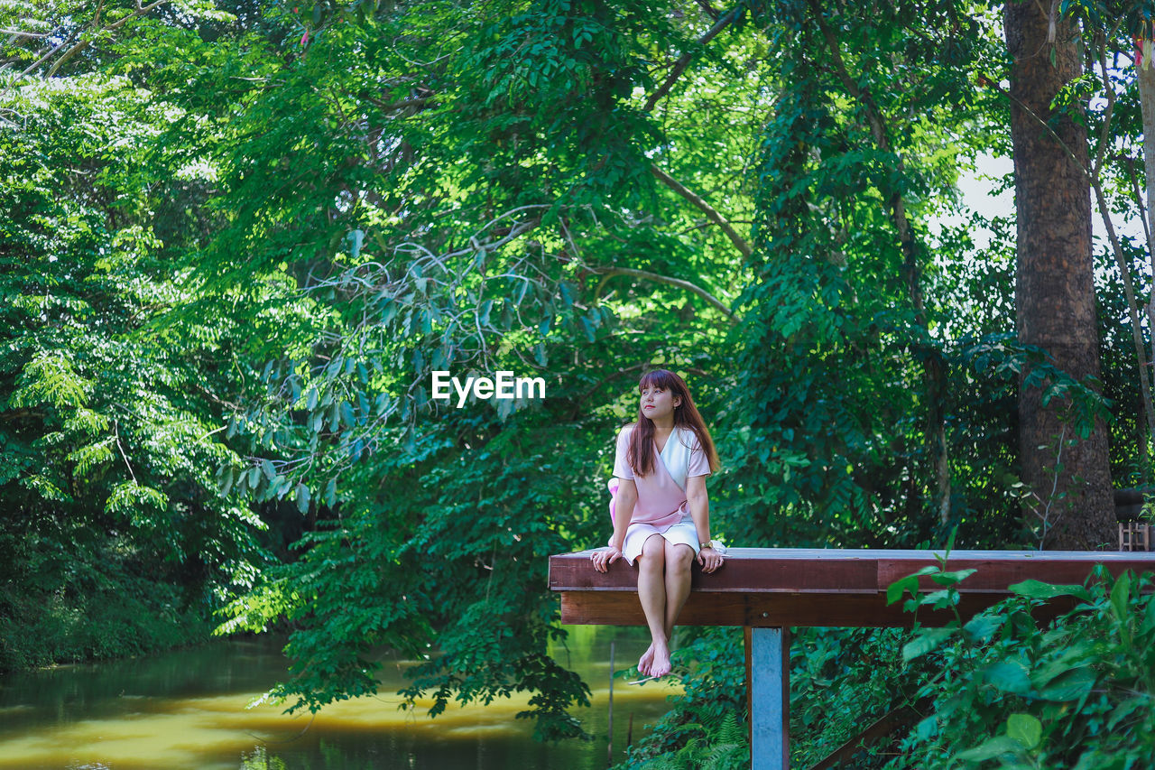 Woman sitting against trees