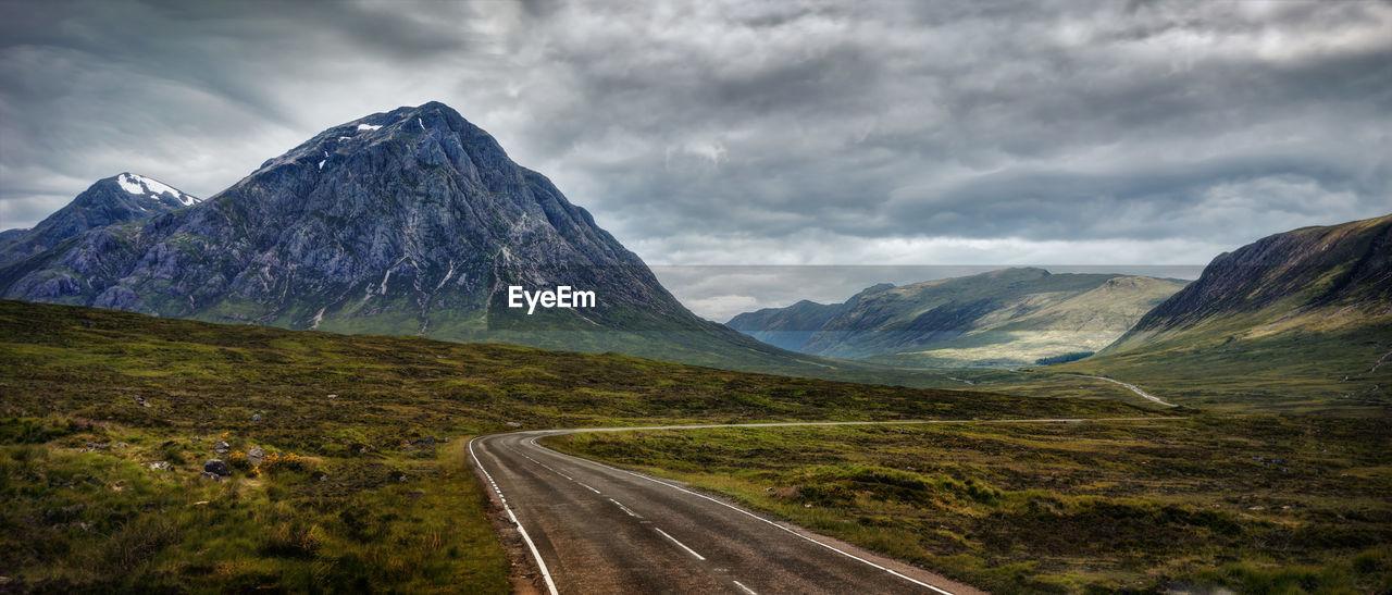 Road leading towards mountains against sky