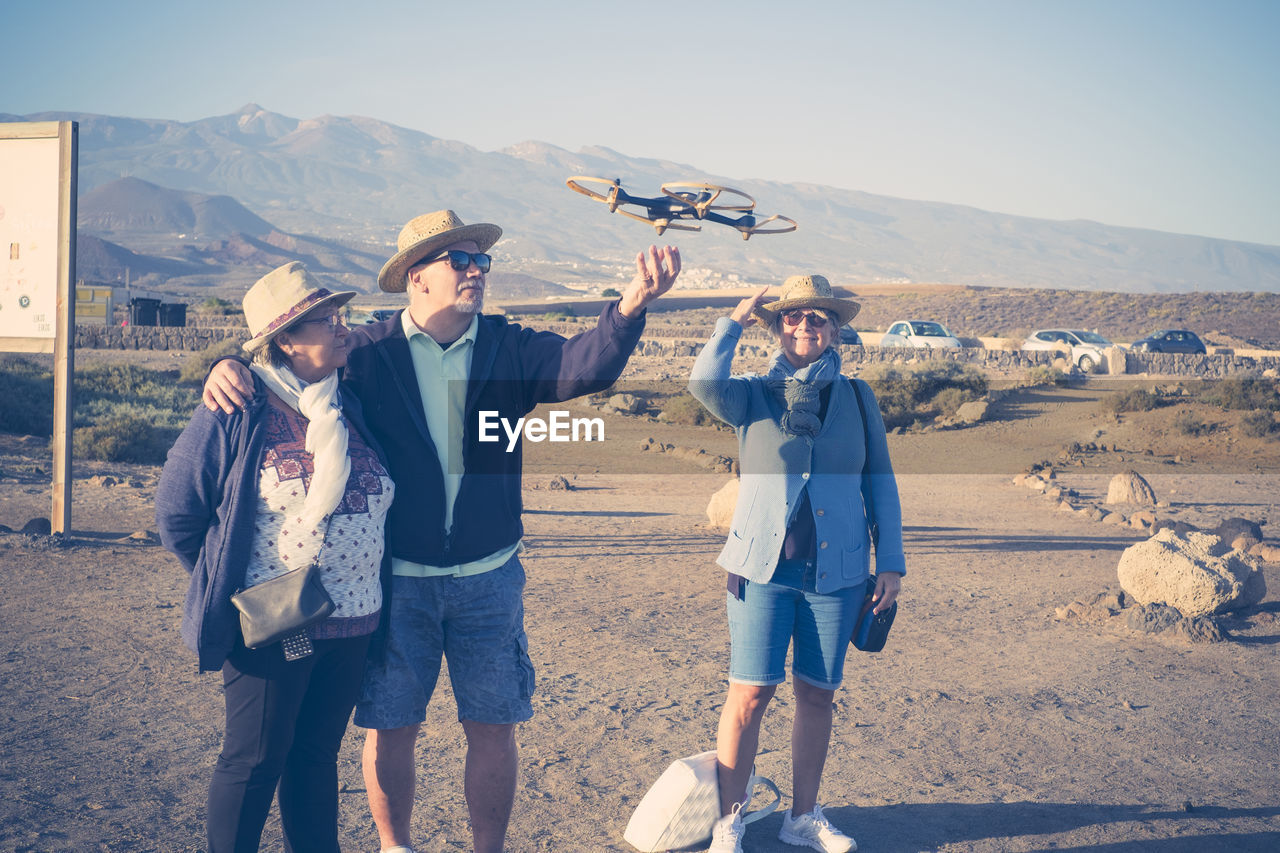 Friends flying drone while standing at desert