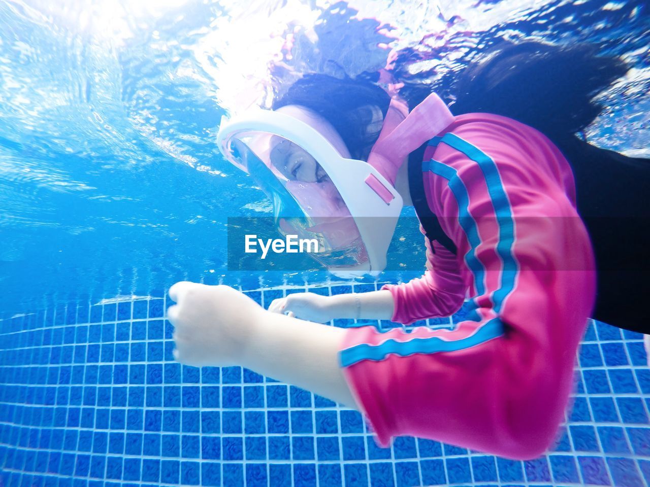 MIDSECTION OF WOMAN SWIMMING IN POOL