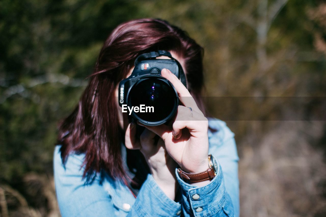 PORTRAIT OF WOMAN WEARING CAMERA