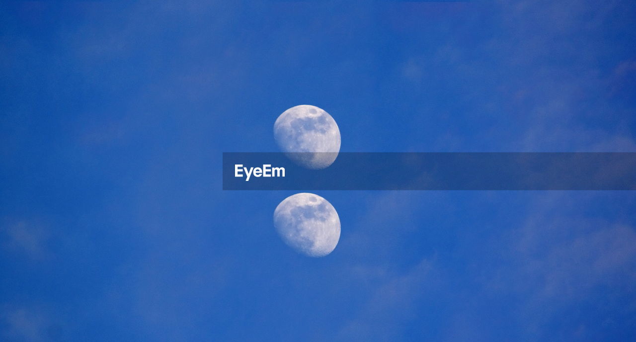 Low angle view of moon in blue sky