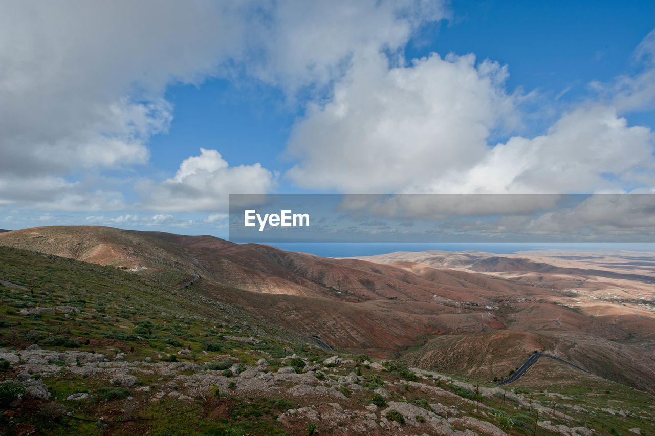 View of arid landscape against cloudy sky