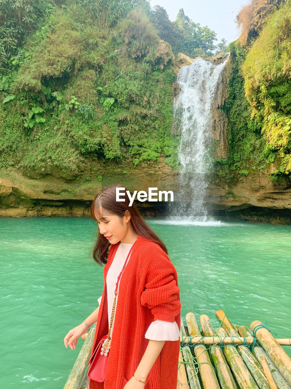 BEAUTIFUL WOMAN LOOKING AWAY AGAINST WATERFALL AND TREES