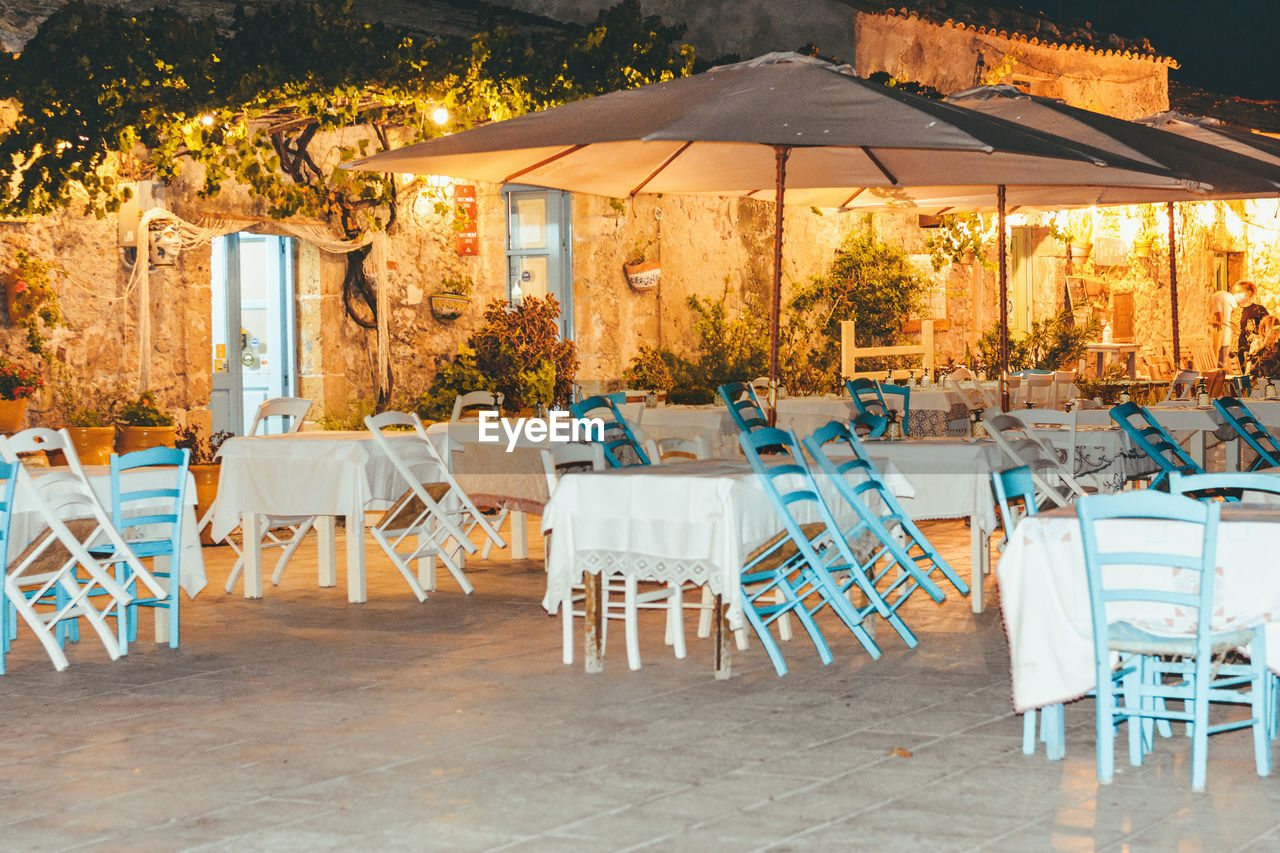 Empty chairs and tables in restaurant against buildings