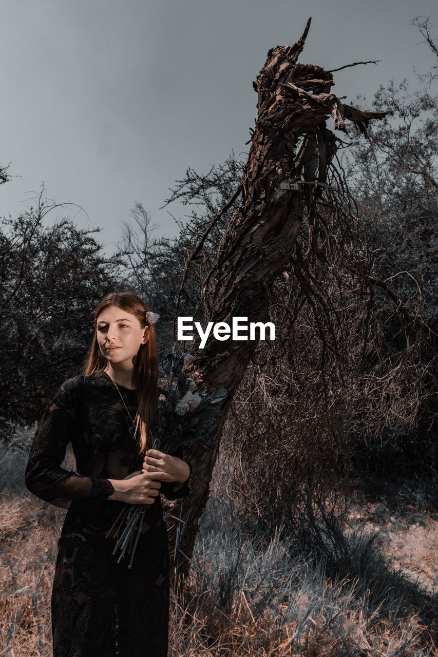 Portrait of woman standing by tree