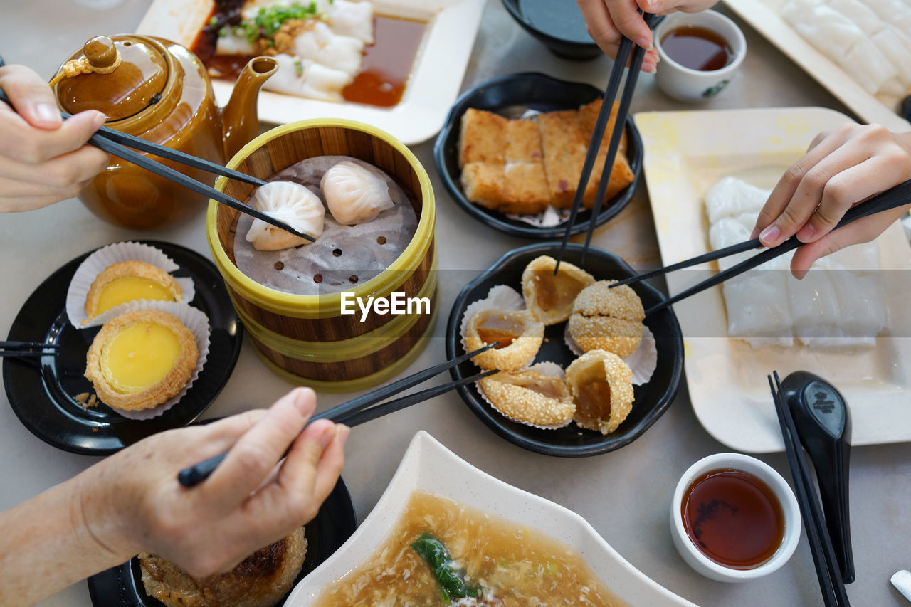 Cropped image of people having food with chopsticks at table