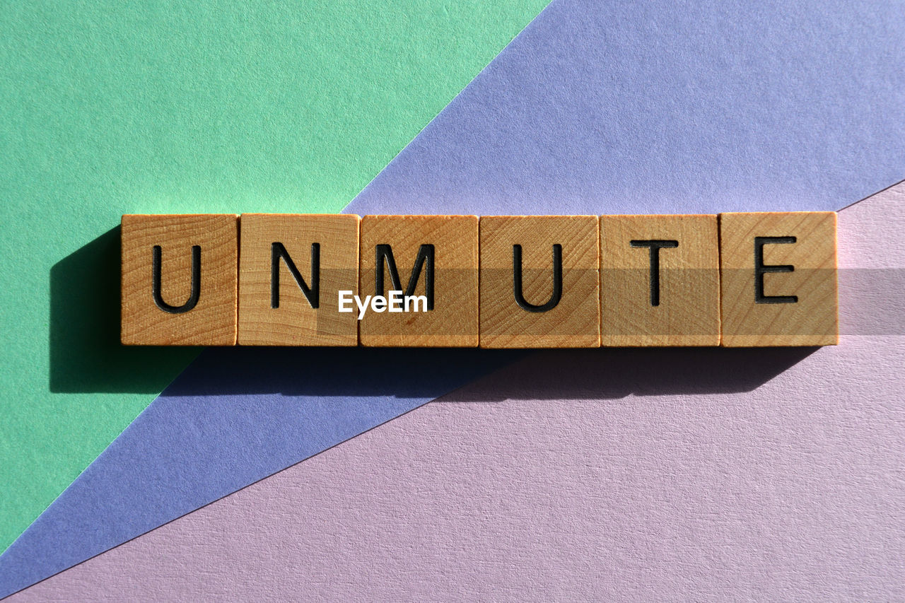 Unmute, word in wooden alphabet letters isolated on background as a banner headline