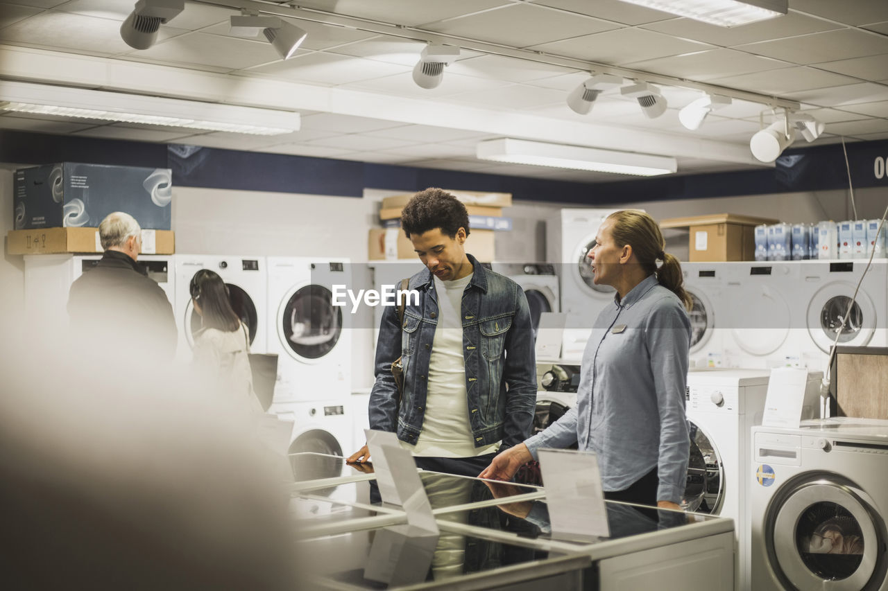 Mature owner talking to male customer in electronics store