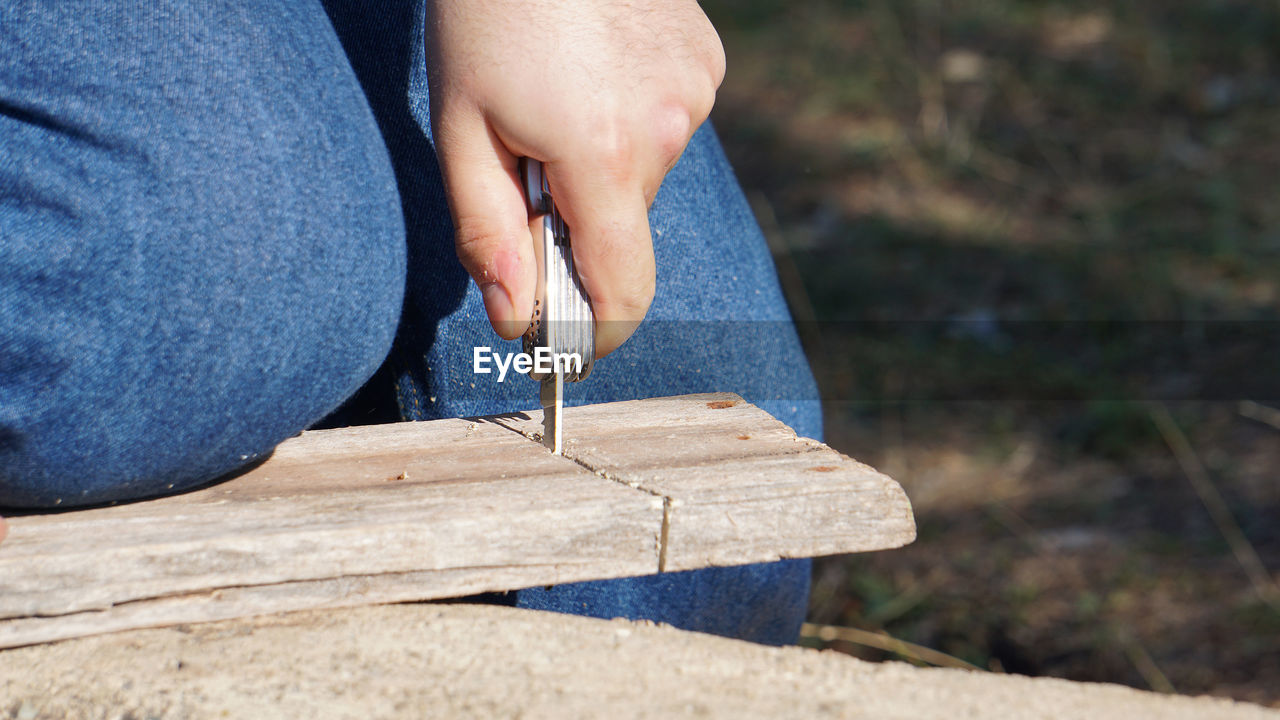 one person, blue, hand, wood, adult, day, close-up, nature, focus on foreground, holding, outdoors, casual clothing, leisure activity, jeans, lifestyles, limb, human leg