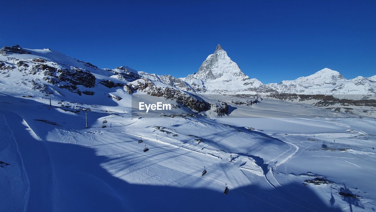 SNOWCAPPED MOUNTAINS AGAINST CLEAR BLUE SKY